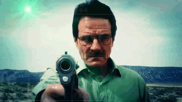 a man wearing glasses is pointing a gun at the camera ..