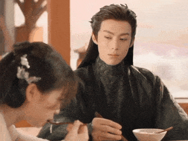 a man and a woman are sitting at a table with chopsticks
