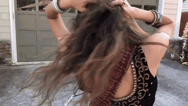 a woman in a black top is holding her hair in a ponytail