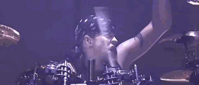 a man wearing a bandana is playing the drums