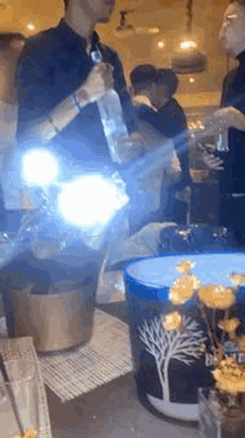 a group of people are standing around a table with a bucket of ice and a bottle of vodka in it .