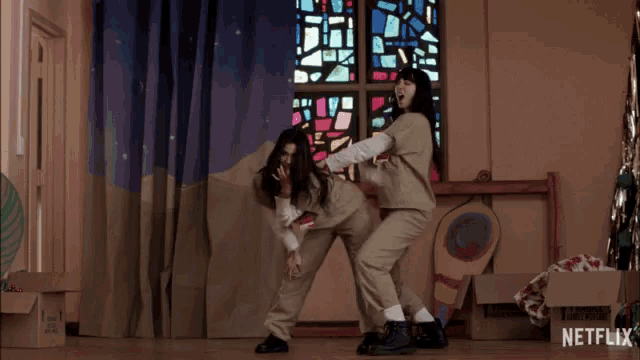 two women are dancing in front of a stained glass window and a box that says netflix