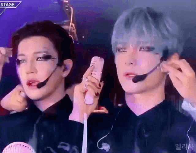 a couple of men are standing next to each other and one of them is wearing a microphone on his ear .