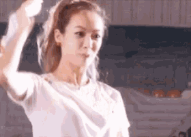 a woman in a white t-shirt is holding a white object in her hand