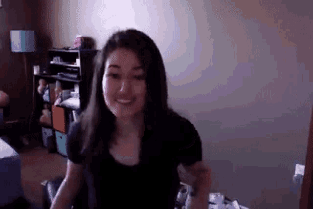 a woman in a black shirt is smiling and looking at the camera
