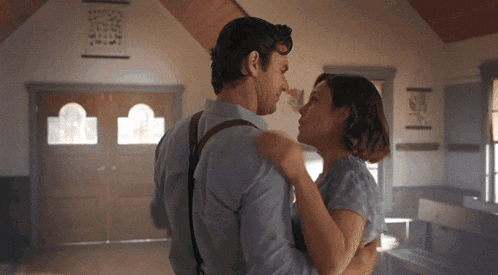 a man and a woman are dancing in a room with a sign on the wall that says ' jesus '