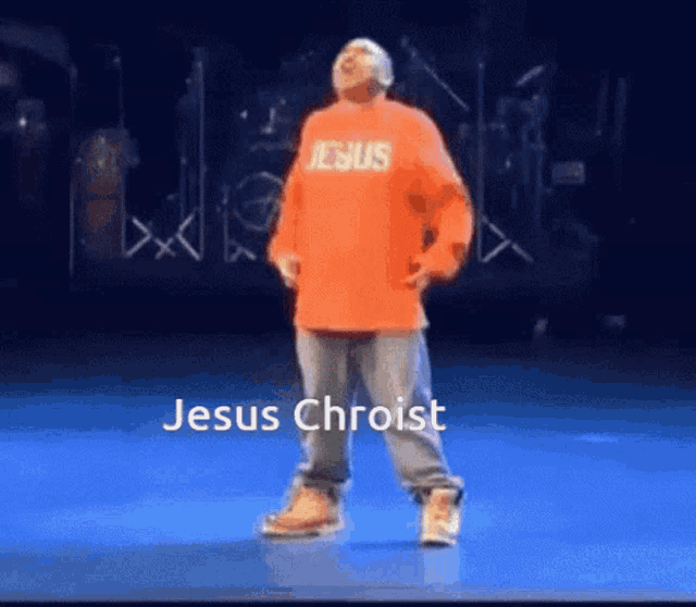a man in an orange jesus shirt is dancing on a stage