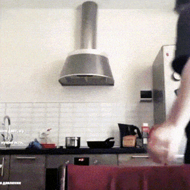 a person is standing in a kitchen with a stainless steel exhaust hood above them