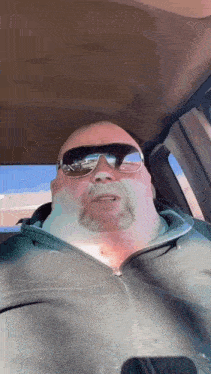 a man with a beard is wearing sunglasses and a black jacket .