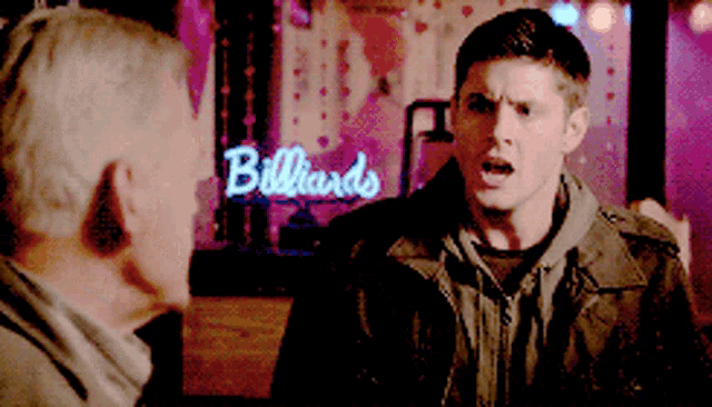 a man is standing in front of a billiards sign