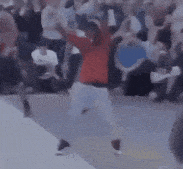 a man in a red jacket is dancing in front of a crowd of people