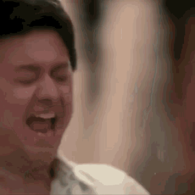 a close up of a man laughing with his mouth open .