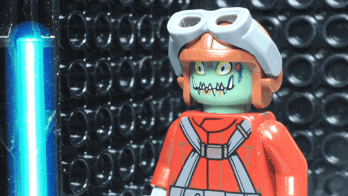 a lego figure is wearing a helmet and goggles and has a green face painted on it