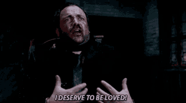 a man is saying i deserve to be loved with his hands in the air .