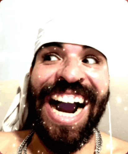 a man with a beard wearing a bandana on his head is smiling