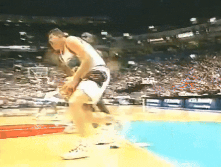 a basketball player is jumping in the air during a game with a crowd watching