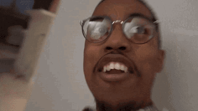 a man wearing glasses is making a funny face with his mouth open and the word no written on his face .