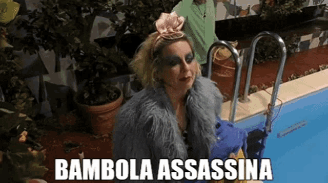 a woman in a fur coat is standing next to a swimming pool with the words bambola assassina written above her