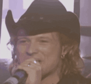 a man wearing a cowboy hat singing into a microphone