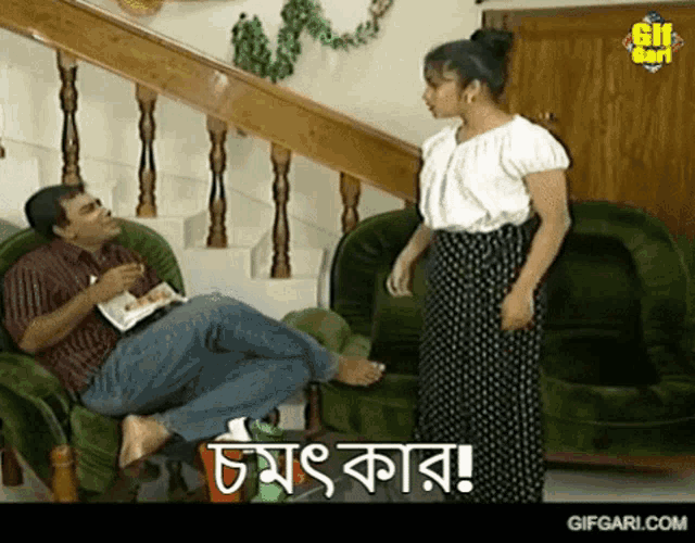 a man sits in a chair while a woman stands in front of him and says " gifgari.com " on the bottom