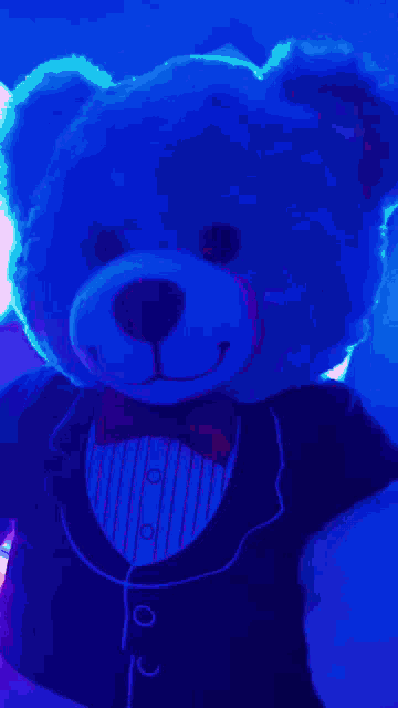 a teddy bear wearing a tuxedo and bow tie is glowing in the dark