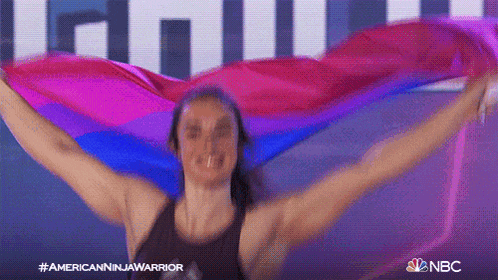a woman is holding a rainbow flag in her arms .