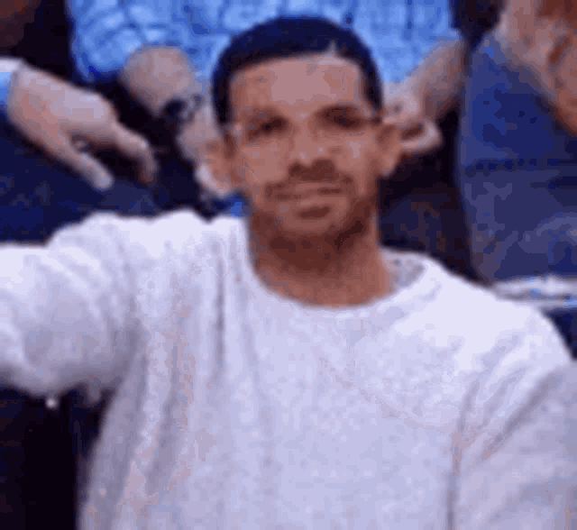 a man in a white sweater is taking a selfie in a basketball stadium .
