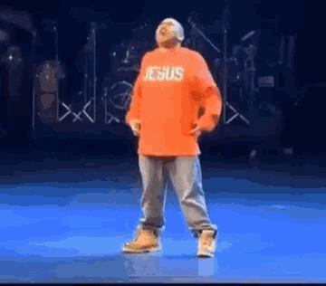 a man is dancing on a stage wearing a red shirt that says `` jesus '' .
