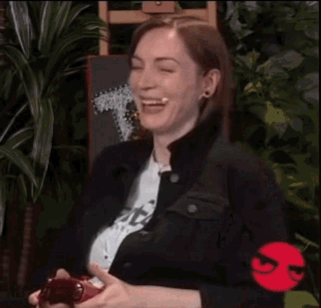 a woman is laughing while holding a video game controller in her hands .
