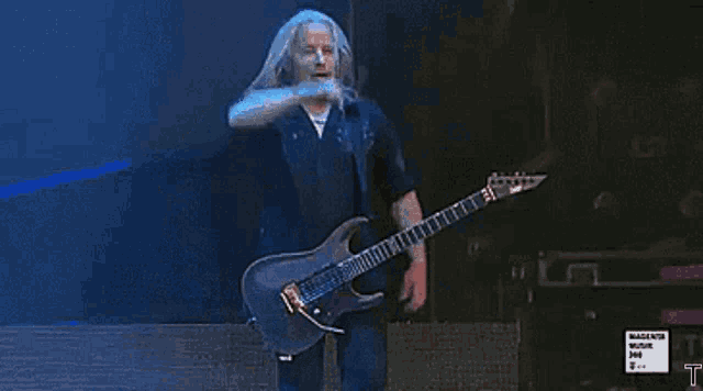 a man playing a guitar on a stage with a sign that says magenta music