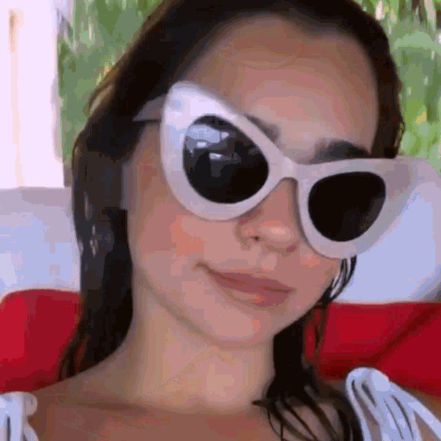 a woman wearing a pair of white sunglasses is smiling