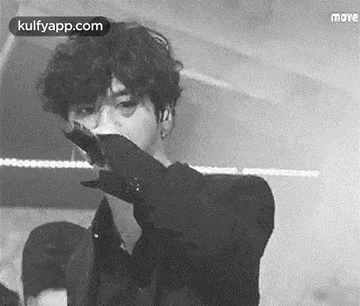 a black and white photo of a person holding a microphone .