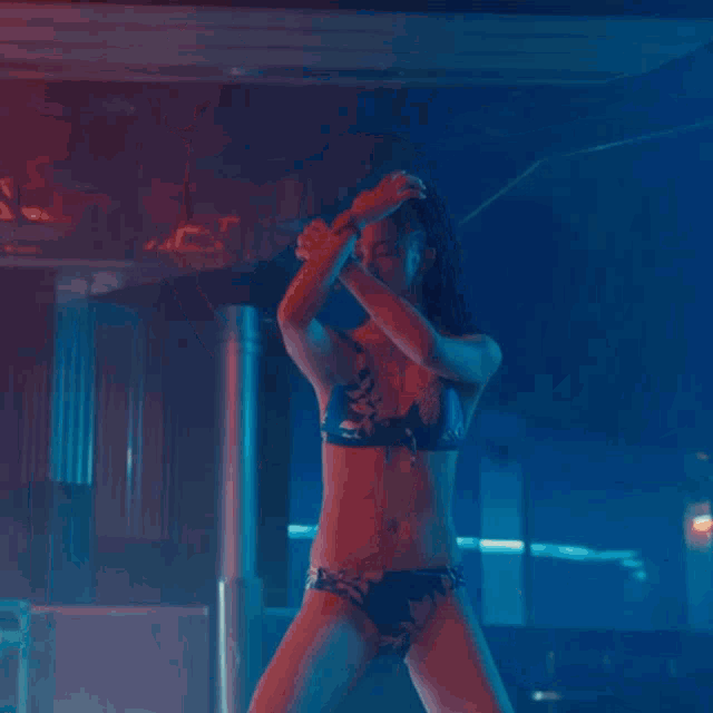 a woman in a bikini is dancing with her hands in the air