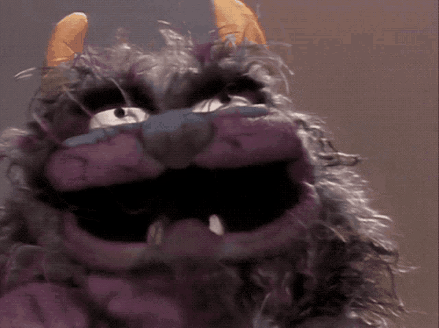 a close up of a stuffed animal with a beard and horns