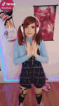 a girl wearing headphones and overalls is standing in front of a wall that says tiktok on it