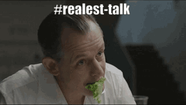 a man in a white shirt is eating lettuce with the words # realest-talk above him