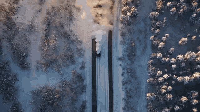 an aerial view of a train going down the tracks in the snow