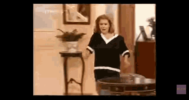 a woman in a black shirt is standing in a living room .
