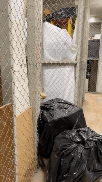 a chain link fence surrounds a room with trash bags