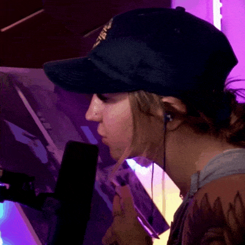 a woman wearing a hat and ear buds looks at a screen