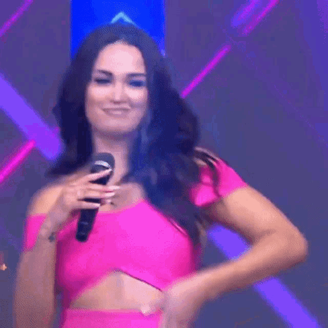 a woman in a pink dress is holding a microphone in her hand .