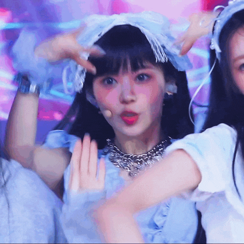 a girl in a blue dress with a bow on her head looks at the camera