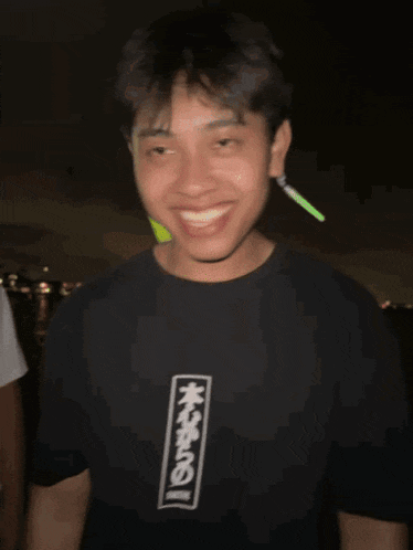 a man wearing a black shirt with chinese writing on it smiles