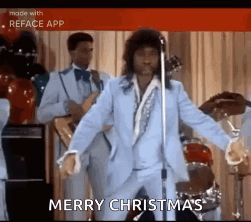 a man in a blue suit is singing into a microphone while dancing on stage .