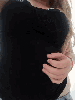 a woman wearing a black tank top and blue shorts shows off her breasts