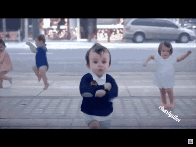 a group of babies are dancing on a sidewalk with the name charlygillori on the bottom left