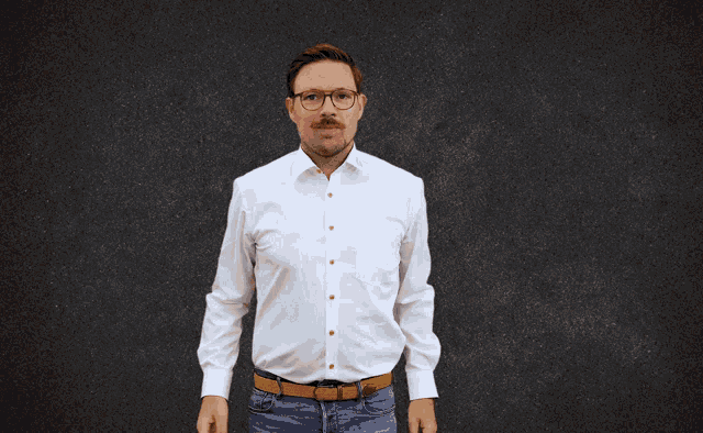a man wearing glasses and a white shirt is holding his fists up in the air
