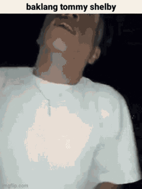 a man in a white shirt is making a funny face while wearing a necklace .