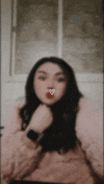 a woman wearing a pink sweater has a heart on her nose