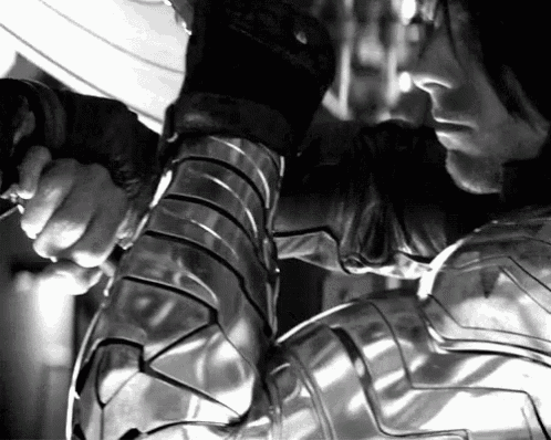 a black and white photo of a man in armor holding a sword .